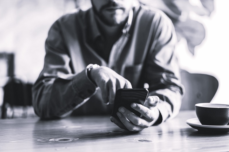 Photo qui montre un homme en train de regarder l'écran de son téléphone portable.